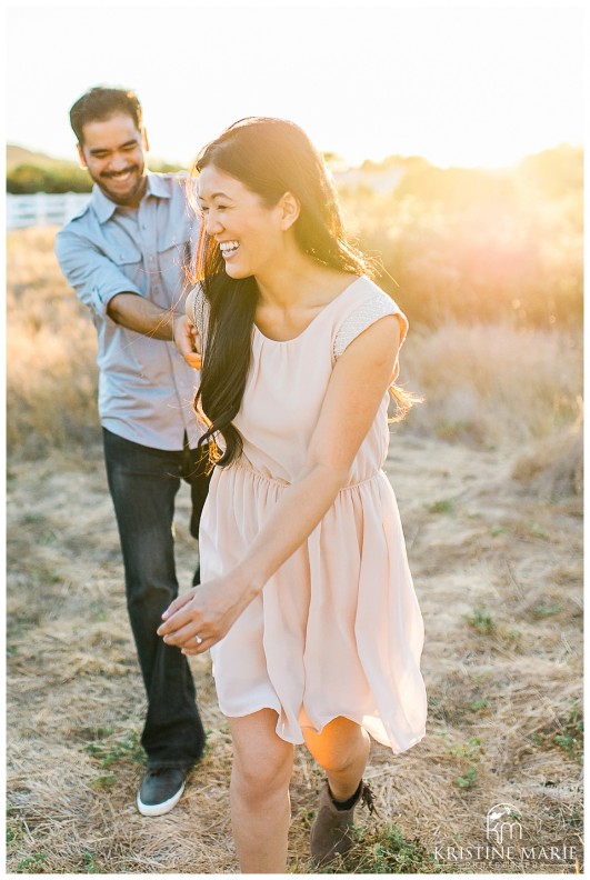 Couple Running Happily in Open Field at Sunset | San Diego Engagement Photographer | Kristine Marie Photography