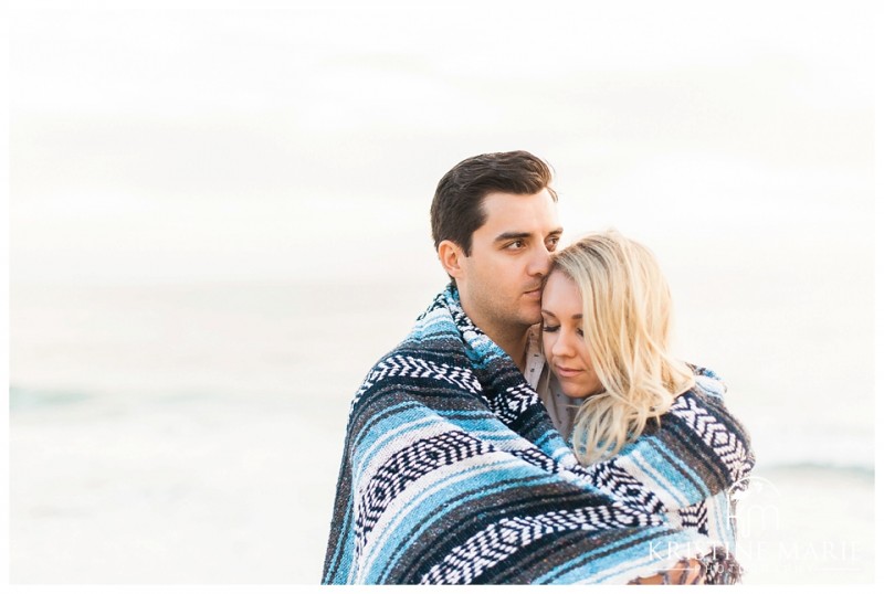 Couples Embrace with Blanket  Windandsea Beach Engagement Photo | La Jolla Wedding Photographer | Kristine Marie Photography | © www.kristinemariephotography.com