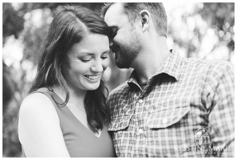 Black and White Photo of Happy Couple Whispering Secret | Engagement in San Diego with Dog | Murphy Canyon San Diego Engagement Photo | Kristine Marie Photography | © www.kristinemariephotography.com