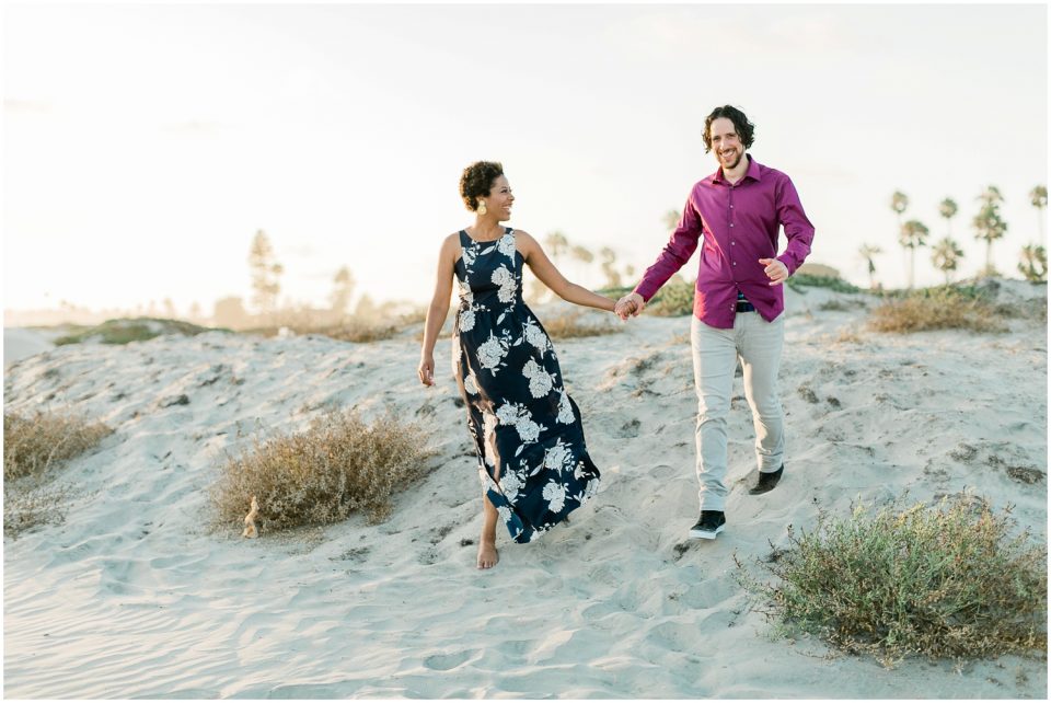 couple running hand in hand on beach Hotel Del coronado Beach Engagement Pictures San Diego Engagement Photographer Kristine Marie Photography