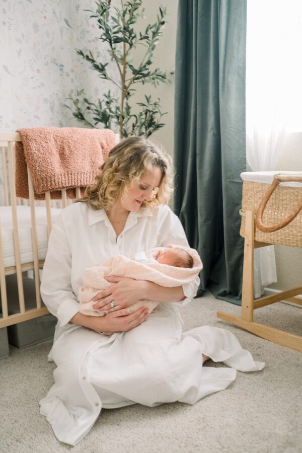 mom holding newborn in nursery | San Diego lifestyle newborn family photographer